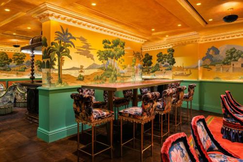 a bar in a restaurant with a table and chairs at The Serangoon House Little India, Singapore, a Tribute Portfolio Hotel in Singapore