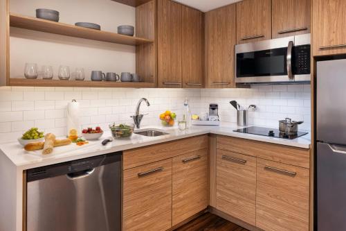 a kitchen with wooden cabinets and a stainless steel refrigerator at Element Minneapolis Downtown North Loop in Minneapolis