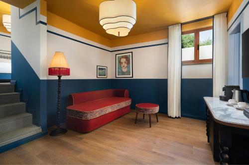 a living room with a red couch and a lamp at Villa Ermellina Siena, a Tribute Portfolio Hotel in Siena
