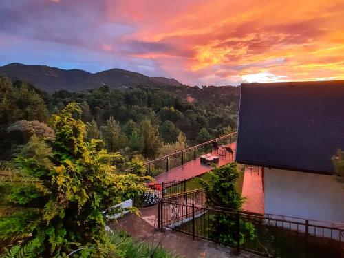 a view of a building with a sunset in the background at Chalés Mirante Monte Verde in Monte Verde