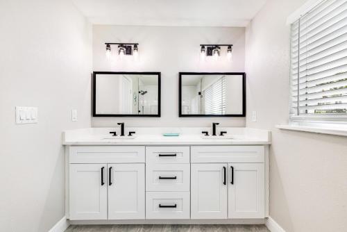 a white bathroom with two sinks and two mirrors at Banyan Beach House in Sanibel Island
