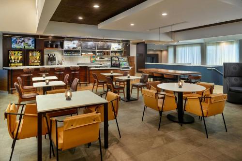 a restaurant with tables and chairs and a bar at Courtyard by Marriott Atlanta Airport South/Sullivan Road in Atlanta
