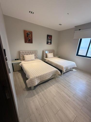 a bedroom with two beds and a window at شالية موج 335 in Dhahran