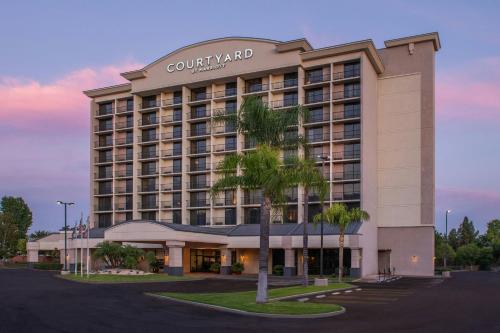 a hotel building with a palm tree in front of it at Courtyard by Marriott Los Angeles Pasadena/Monrovia in Monrovia