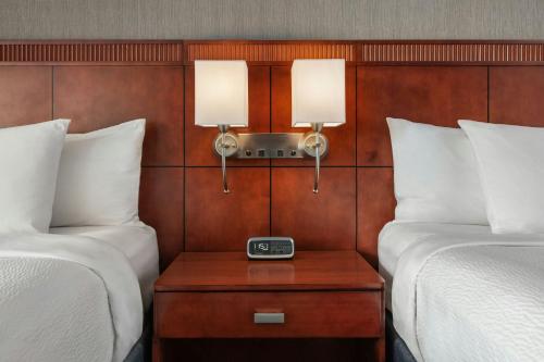 a room with two beds and a table with a clock at Courtyard by Marriott Los Angeles Pasadena/Monrovia in Monrovia