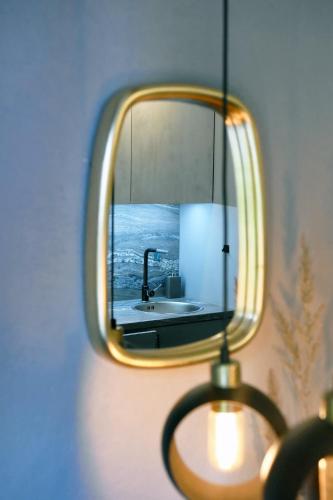 a mirror hanging on a wall with a sink at LOCUSDO Apartment No.31 in Mažeikiai