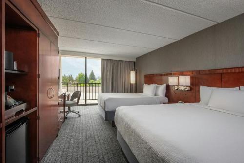 a hotel room with two beds and a balcony at Courtyard by Marriott Los Angeles Pasadena/Monrovia in Monrovia
