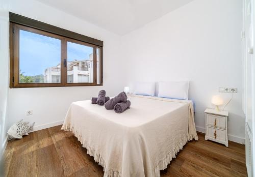 a white bedroom with a bed with a window at Apartamento en primera línea Javea in Jávea