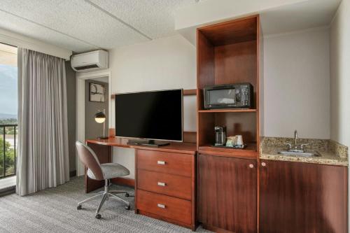 a hotel room with a television and a desk with a chair at Courtyard by Marriott Los Angeles Pasadena/Monrovia in Monrovia
