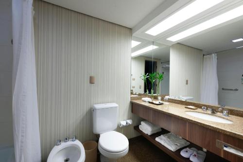 a bathroom with a toilet and a sink and a mirror at Marriott São Paulo Airport Hotel in Guarulhos