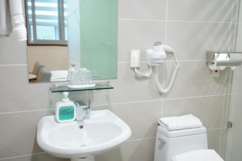 a white bathroom with a sink and a mirror at Rosana Hotel in Seoul