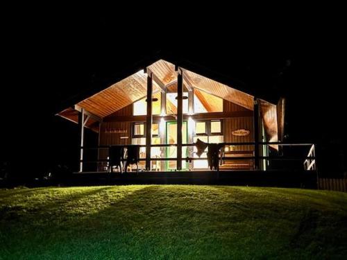 a house with a dog standing outside of it at night at Bell Rock Holiday Lodge in Killin