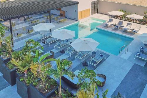 an overhead view of a swimming pool with tables and umbrellas at City Express Plus by Marriott Mazatlan in Mazatlán