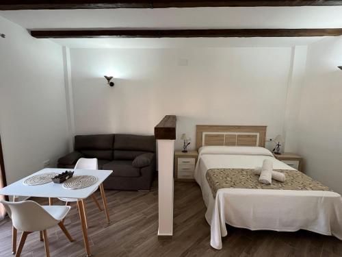 Un dormitorio con una cama, un sofá y una mesa. en Apartamentos Los Belloso, en Alange