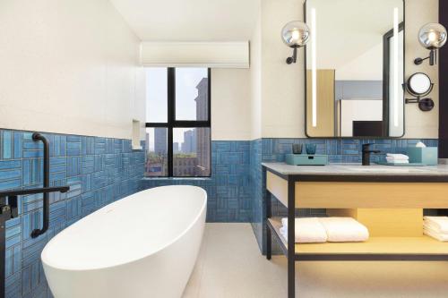 a bathroom with a tub and a sink and a mirror at Four Points by Sheraton Ji’an in Ji'an