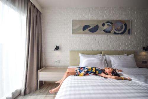 a woman laying on a bed with a toy at Shama Yen-Akat Bangkok in Bangkok