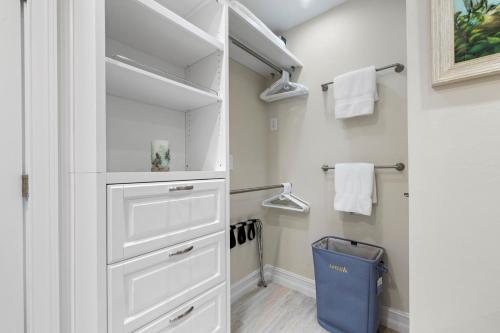a walk in closet with white cabinets and a blue trash can at Sandpiper Beach 205 in Ybel