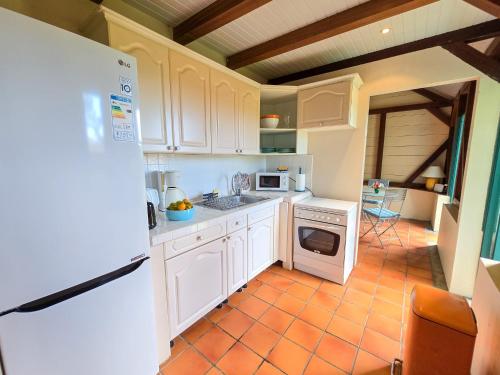 a kitchen with white cabinets and a white refrigerator at La Case à Lucie in Saint-Pierre
