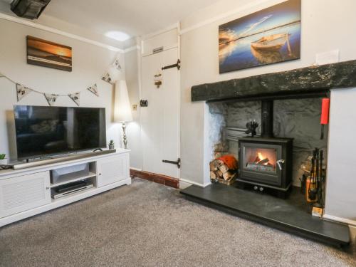 a living room with a fireplace and a tv at Tan Yr Allt in Pwllheli