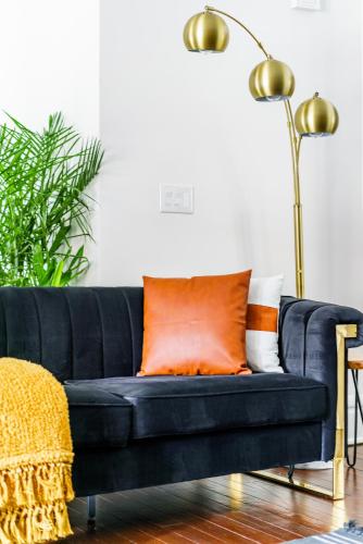 a black couch with an orange pillow in a living room at Prime Location Top Rated Clean Parking Free! in Columbus