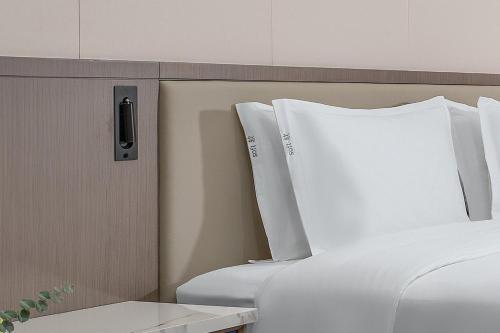 a bed with white sheets and a remote control on a wall at Holiday Inn Express Lanzhou Downtown by IHG in Lanzhou