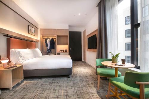 a hotel room with a bed and a table and chairs at Holiday Inn Melbourne Bourke Street Mall by IHG in Melbourne