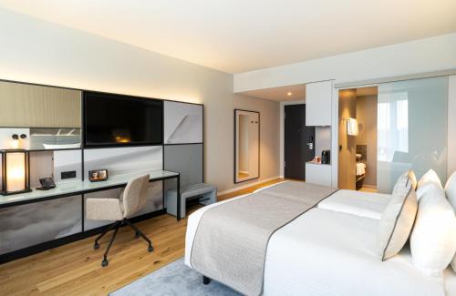 a hotel room with a bed and a desk and a tv at Leonardo Royal Hotel Cologne Bonn Airport in Cologne