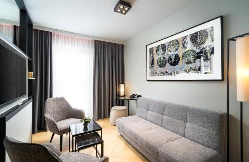 a living room with a couch and chairs at Leonardo Royal Hotel Cologne Bonn Airport in Cologne