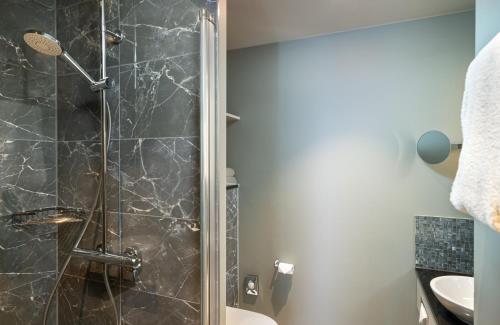 a bathroom with a shower with a toilet and a sink at Leonardo Royal Hotel Cologne Bonn Airport in Cologne