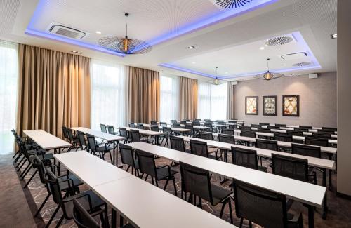 an empty lecture room with tables and chairs at Leonardo Royal Hotel Cologne Bonn Airport in Cologne