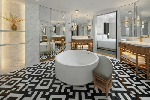 a bathroom with a bath tub and a bedroom at The Laurus, a Luxury Collection Resort, Singapore in Singapore
