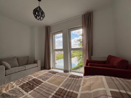 a bedroom with a bed and a large window at Apartament nad Wartą Śrem in Śrem