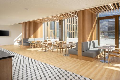 a lobby with tables and chairs in a building at Holiday Inn Express & Suites Sion by IHG in Sion