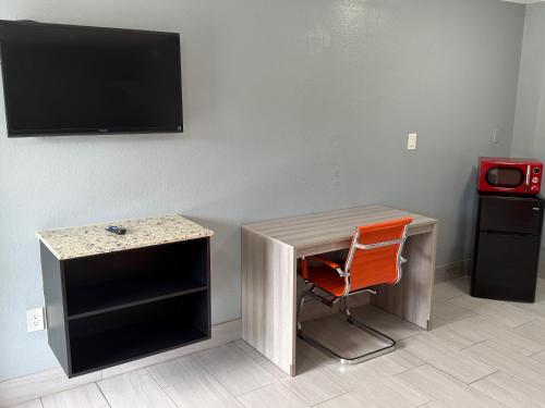 a desk and a chair in a room with a television at Apollo Inn - Downtown in Kissimmee