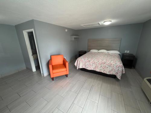 a bedroom with a bed and an orange chair at Apollo Inn - Downtown in Kissimmee