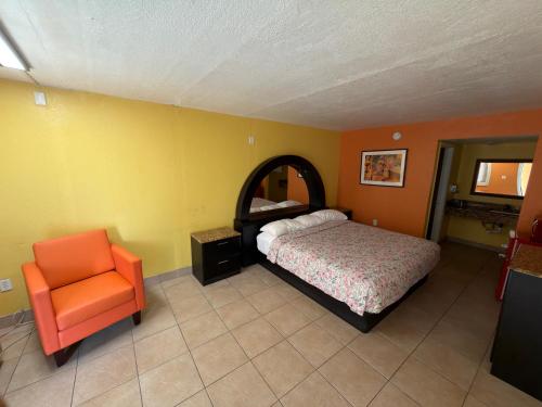 a bedroom with a bed and an orange chair at Apollo Inn - Downtown in Kissimmee