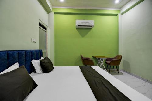 a bedroom with a bed and a green wall at SPOT ON Hotel The Baithak & Restaurant in Etāwah