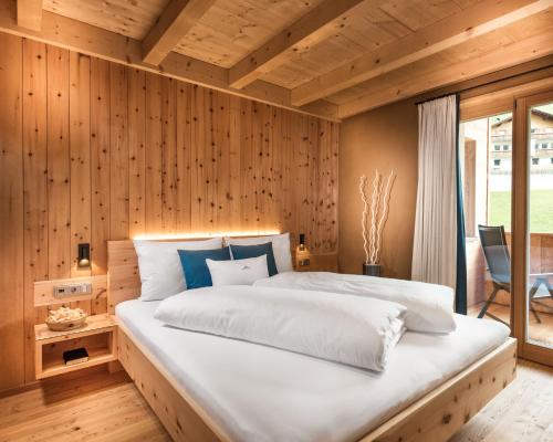 a bedroom with a large white bed with wooden walls at Chalet Rudana in Sesto