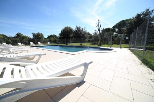 a swimming pool with white lounge chairs and a fence at Il Vignone - Castagneto Carducci in Castagneto Carducci