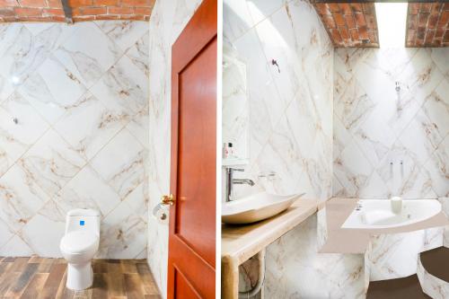 a bathroom with white marble walls and a toilet and a sink at Capital O Hotel Posada Terraza, Tequila Jalisco in Tequila