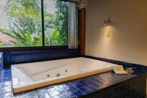 a bath tub in a bathroom with a window at Hosteria Las Quintas Hotel Restaurante Bar in Cuernavaca