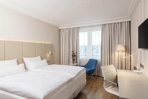 a hotel room with a white bed and a blue chair at NH Vienna Airport Conference Center in Schwechat