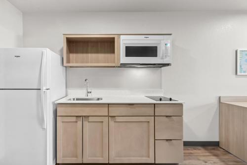 a kitchen with a white refrigerator and a sink at WoodSpring Suites Tucson Medical Center in Tucson