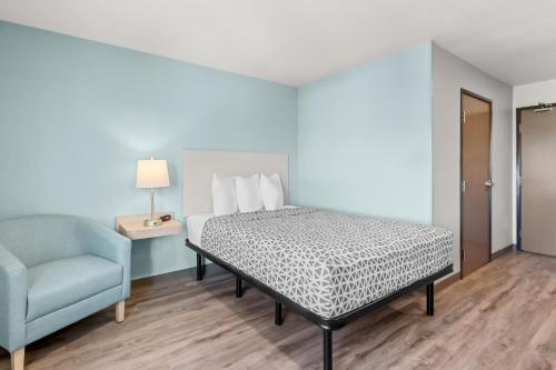 a bedroom with a bed and a blue chair at WoodSpring Suites Tucson Medical Center in Tucson