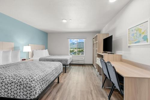 a hotel room with two beds and a desk and a television at WoodSpring Suites Tucson Medical Center in Tucson