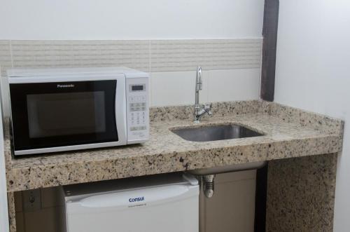 a kitchen counter with a microwave and a sink at Pousada da Encosta in Garopaba