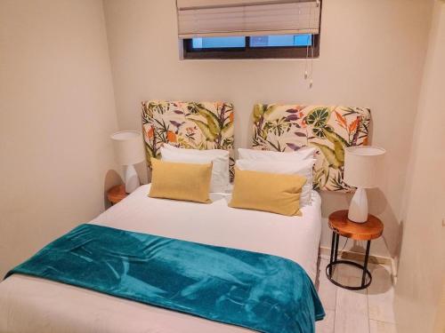 a bedroom with a bed with white sheets and yellow pillows at Zimbali Hotel Unit 422 Suites in Ballito