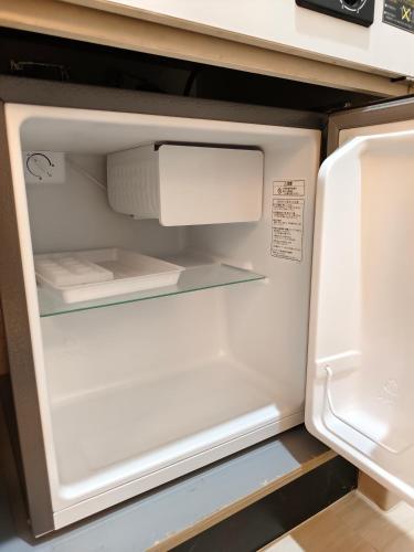 an empty refrigerator with its door open in a kitchen at THE ONE kouennji in Tokyo