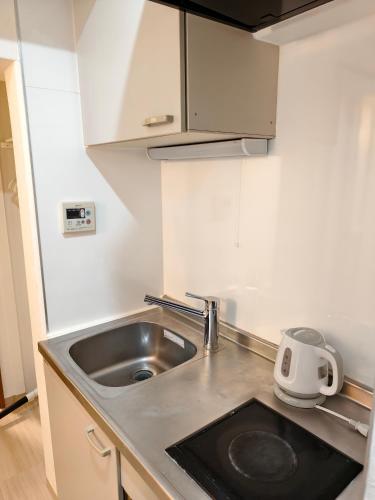 a small kitchen with a sink and a microwave at THE ONE kouennji in Tokyo