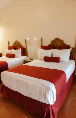 two beds with red and white sheets in a room at Hosteria Las Quintas Hotel Restaurante Bar in Cuernavaca